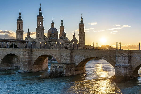 Cathedral of Our Lady of the Pillar and stone bridge at sunset. Zaragoza, Aragon, Spain