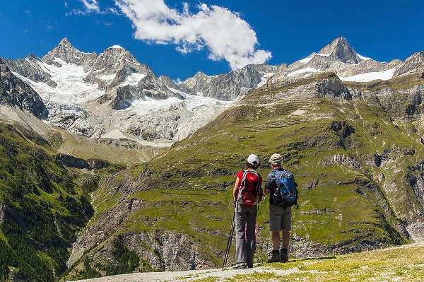 Two caucasian hikers watching the panorama over Swiss alps in Zermatt, Wallis, Switzerland