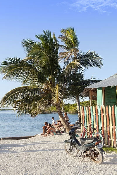 Central America, Belize, Belize district, Caye Caulker, tourists sit on the tiny beach