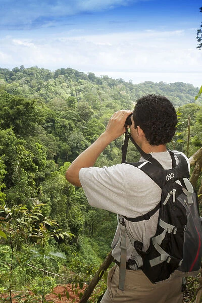 Central America, Costa Rica, Osa Peninsula, a rainforest guide looking through binoculars