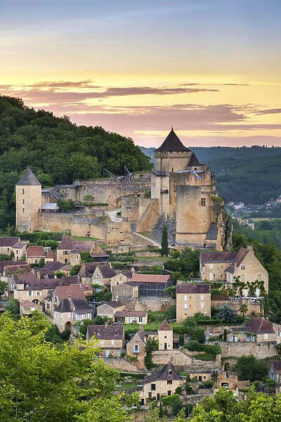 Chateau de Castelnaud castle and village over Dordogne River valley at sunset