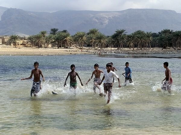 Children enjoy a boat race in a lagoon at Qalansiah