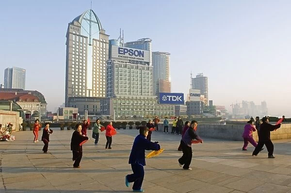 China, Shanghai. Tai-chi performers in front of modern buildings