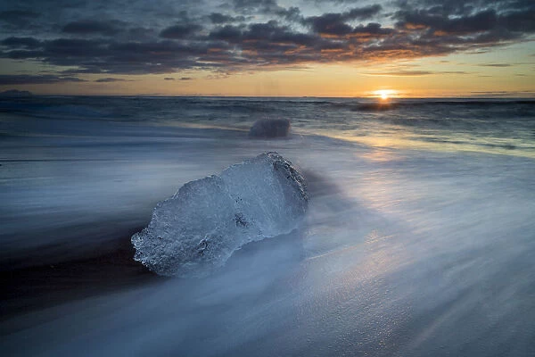 Chunk of ice on shore at Diamond beach near Jokulsarlon glacier lagoon during sunrise
