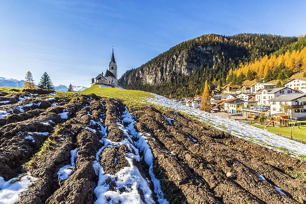The church of Schmitten surrounded by colorful woods and snow Albula District Canton