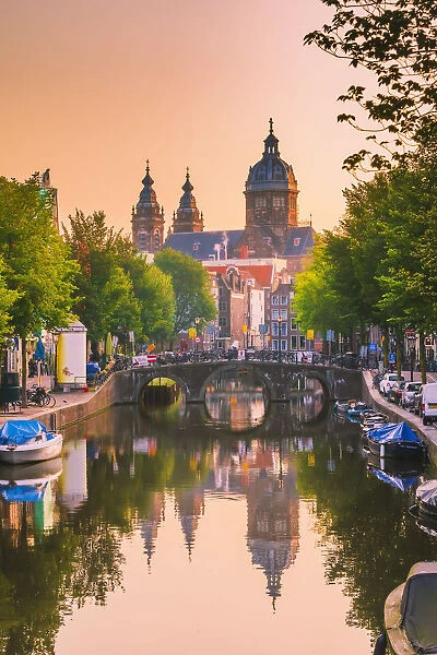 Church of St Nicholas reflecting in the canal at sunrise on a summer evening in Amsterdam