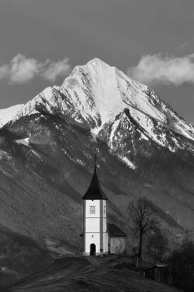 Church of St Primoz with snow capped peak of Storzic in the Kamnik-savinja Alps, Jamnik