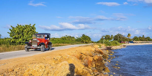 A classic car driving in Playa Ancoa, in Trinidad, Sancti Spiritus, Cuba