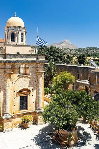 Clear sky over the dome and Greek flag hanging on ancient Agia Triada of Tzagarolon monastery, Crete island, Greece