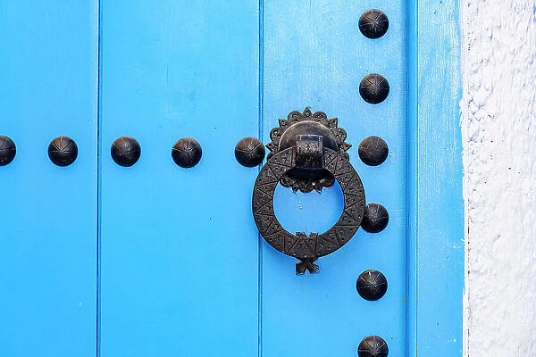 Close up of blue knobbed doorway on white wall background in the old alleys of Medina, Chefchaouen, Morocco