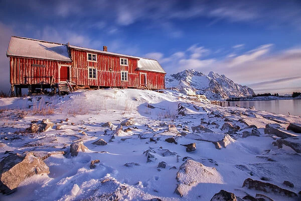 Clouds run over a typical red house of Henningsvaer. Lofoten Islands. Norway