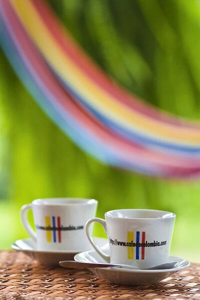 Colombia, Caldas, Manizales, Hacienda Venecia, Coffee cups on table with hammock in