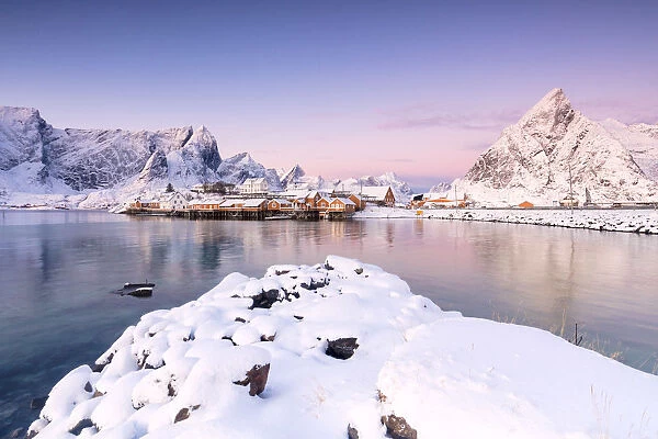 The colors of dawn frames the fishermen houses surrounded by snowy peaks Sakrisoy Reine Nordland Lofoten Islands Norway Europe