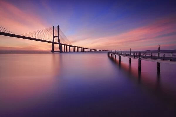 The colors of dawn on Vasco da Gama Bridge that spans the Tagus River in Parque das NaA'A§A'Aµes Lisbon Portugal Europe