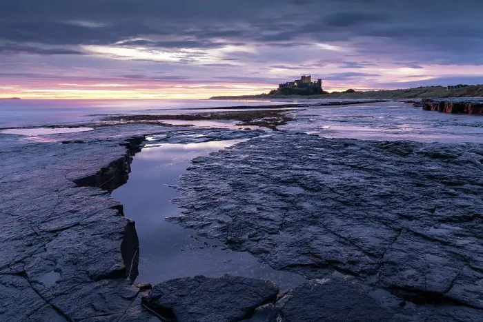 Framed Print : Colourful dawn sky above Bamburgh Castle on the Northumberland coast, England. Autumn (October) 2021