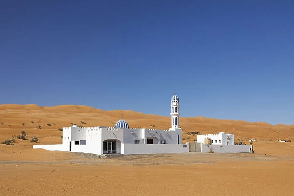 A colourful mosque stands in front of sand dunes at the edge of the desert, Wahiba sands