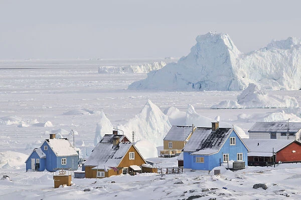 Colourful row of houses with icebergs in the background, Qeqertarsuaq, Disko Island