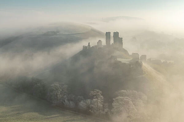 Corfe Castle emerging from mist on a frosty wintry morning, Dorset, England. Winter (February) 2023