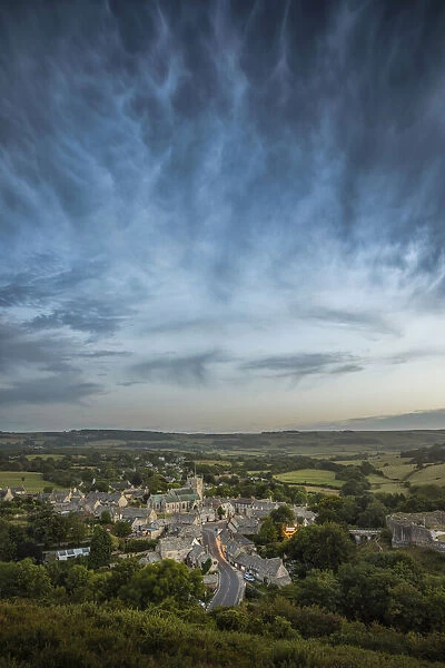 Corfe Castle village with storm clouds above viewed from East Hill, Dorset, England, UK