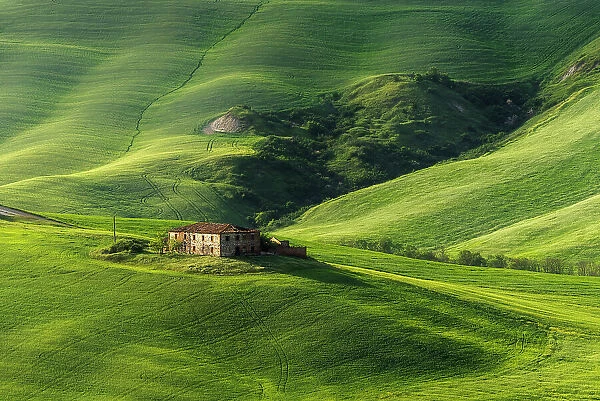 Country house and some rolling hills on a sunny spring afternoon in the Crete Senesi. Tuscany, Italy