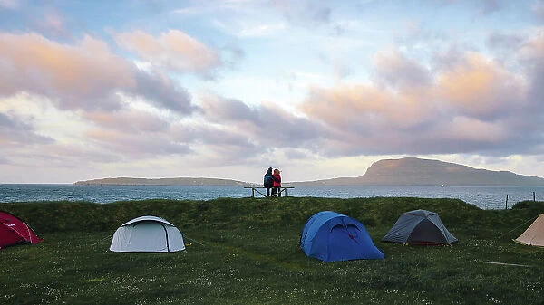 A couple enjoying the sunset in a camping site in Torshavn. In the background the island of Nolsoy
