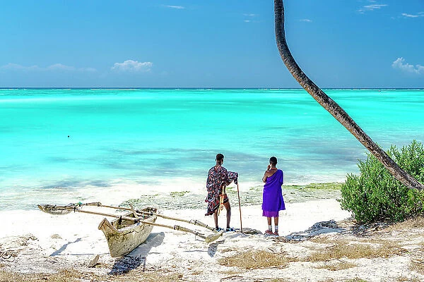 Couple of Maasai with dhow admiring the crystal turquoise sea standing on a white coral beach, Zanzibar, Tanzania (MR)