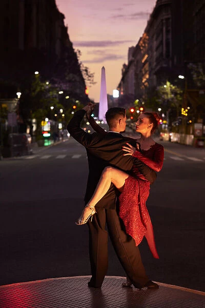 A couple of Professional Tango dancers with the Obelisk monument in background at twilight, Microcentro, Buenos Aires, Argentina. (MR)