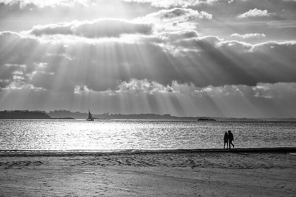 A couple walk along the plage du Mole at sunset, St
