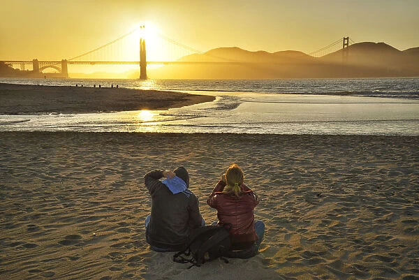 Couple watching sunset at Golden Gate Bridge, Crissy Field, San Francisco, California