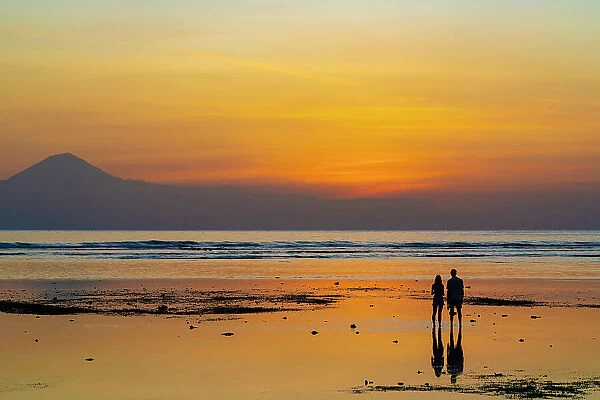 Couple watching sunset on low tide, Gili Trawangan, Lombok, Indonesia