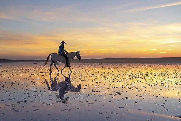 Cowboy riding horse on salt Lake Tuz at sunset, Karamollausagi, Sereflikochisar, Ankara Province, Central Anatolia Region, Turkey