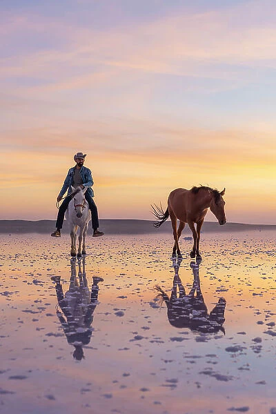 Cowboy riding horse on salt Lake Tuz at sunset, Karamollausagi, Sereflikochisar, Ankara Province, Central Anatolia Region, Turkey