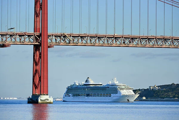 A cruise ship in the Tagus river, leaving the port of Lisbon, passes beneath the 25