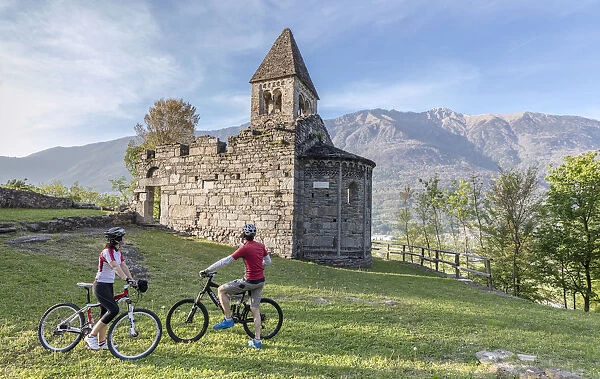 Cyclists admire the ancient Abbey of San Pietro in Vallate in spring Piagno Sondrio