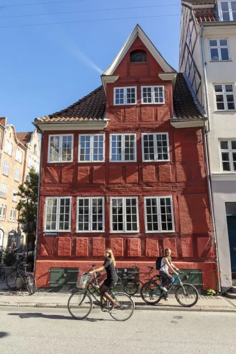 Framed Print : Cyclists pass an old red house in Central Copenhagen, Copenhagen, Denmark Framed Print : Cyclists pass an old red house in Central Copenhagen, Copenhagen, Denmark