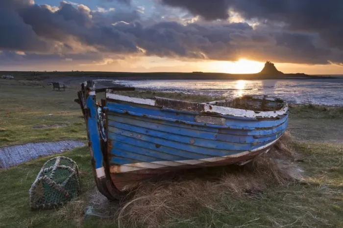 Framed Print : Decaying fishing boat on Holy Island at dawn, with Lindisfarne Castle beyond, Northumberland