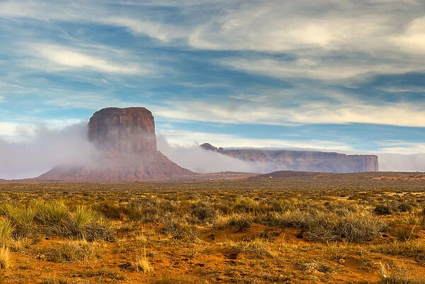 Desert landscape with butte surrounded by low fog, Monument Valley Navajo Tribal Park