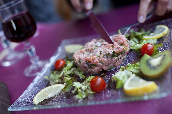 A diner cutting into steak tartare in a restaurant in paris France