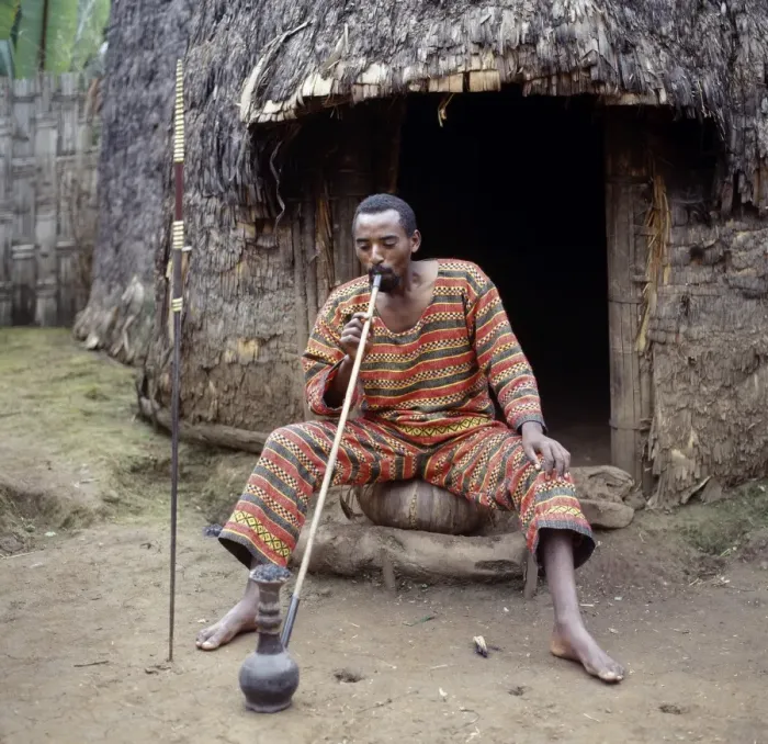 Framed Print : A Dorze man sits outside his home smoking locally-grown Framed Print : A Dorze man sits outside his home smoking locally-grown