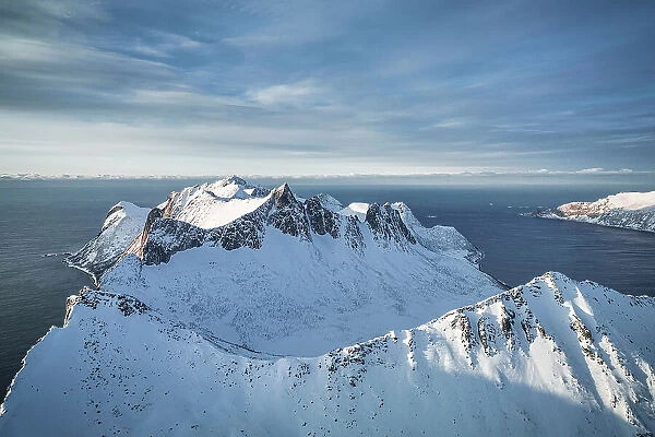 Dramatic sky over the snowcapped peaks of Hesten and Ytste-Kongen mountains, aerial view, Senja, Troms county, Norway