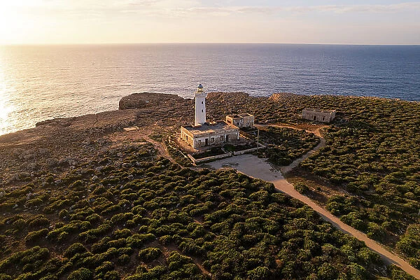 Drone view of the lighthouse Capo Murro di Porco standing on top of a cliff surrounded by Ionian sea at sunrise, Plemmirio marine park, Syracuse, Sicily, Italy