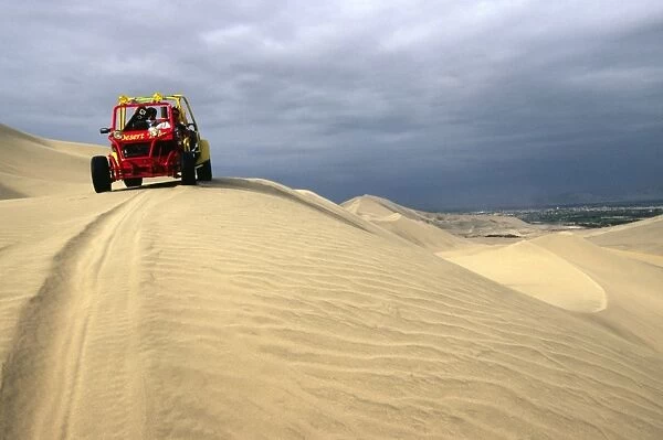 A dune buggy on the sand dunes bordering the city of Ica
