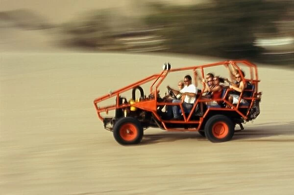 A dune buggy speeds tourists acoss through the sand