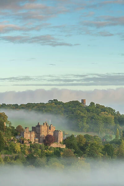 Dunster Castle emerges from swirling morning mist, Exmoor National Park, Somerset, England. Autumn (October) 2022