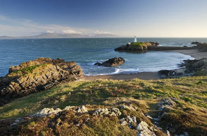 Framed Print : Early evening view of Pilots Cove and the beacon lighthouse T?r Bach on Llanddwyn Island