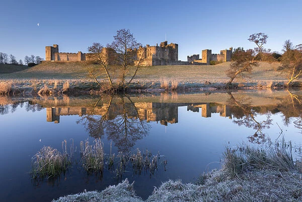 Early morning sunshine illuminates Alnwick Castle in Northumberland, England. Winter