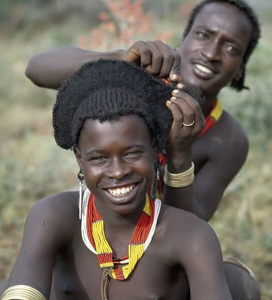 An elaborate hairstyle of a young Hamar man nears completion
