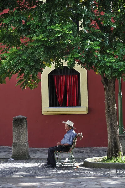 Elderly man sat in Plaza at Iglesia de la Merced, Comayagua, Central America, Honduras
