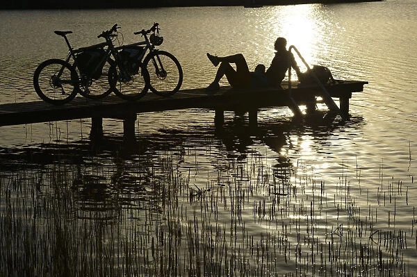 Electric cyclists on jetty, Klostersee Castle Seeon, Chiemgau, Upper Bavaria, Bavaria