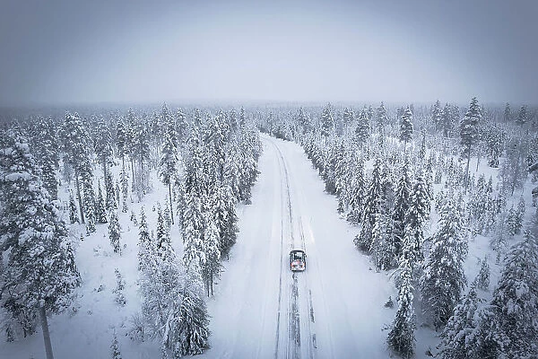 Elevated car along the snowy empty road in the frosty wood, Pallas-Yllastunturi National Park, Muonio, Lapland, Finland